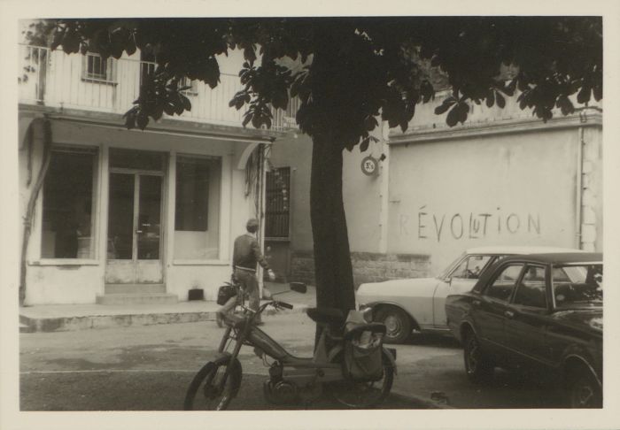 Mobylette et voitures stationnées devant une boutique de prêt-à-porter et chaussures avant travaux à Saint-Céré (28 Fi 24)